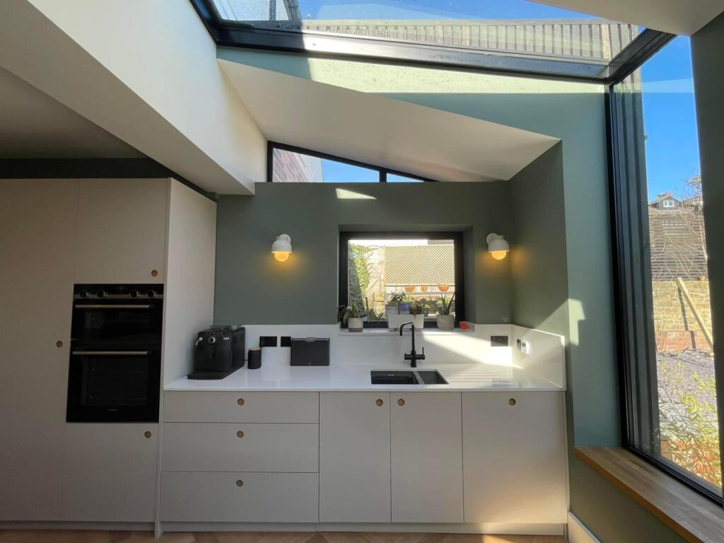 Fitted kitchen with handleless cabinets, skylight and sage green walls